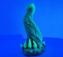 Load image into Gallery viewer, A coated color "Doomstick" tentacle themed adult toy shown from the side in UV lighting.
