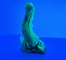 Load image into Gallery viewer, A coated color "Doomstick" tentacle themed adult toy shown from the side in UV lighting.