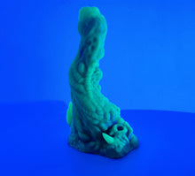 Load image into Gallery viewer, A coated color "Doomstick" tentacle themed adult toy shown from the side in UV lighting.