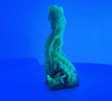 Load image into Gallery viewer, A coated color "Doomstick" tentacle themed adult toy shown from the side in UV lighting.