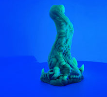 Load image into Gallery viewer, A coated color "Doomstick" tentacle themed adult toy shown from the side in UV lighting.