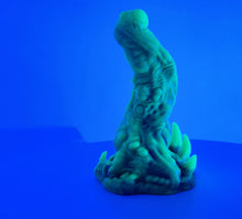 Load image into Gallery viewer, A coated color "Doomstick" tentacle themed adult toy shown from the side in UV lighting.