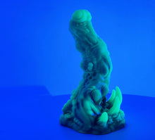 Load image into Gallery viewer, A coated color "Doomstick" tentacle themed adult toy shown from the side in UV lighting.