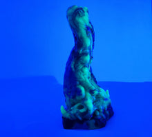 Load image into Gallery viewer, A three color marble "Doomstick" tentacle themed adult toy shown from the side under UV lighting.
