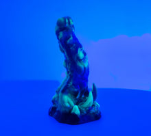 Load image into Gallery viewer, A three color marble "Doomstick" tentacle themed adult toy shown from the side under UV lighting.