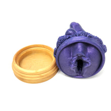 Load image into Gallery viewer, A silicone penetratable sculpture of Jet Setting Jasmine in dark, shimmery purple laying on her side showing her vulva sculpture underside. This is next to her gold stand silicone base, all on a white background.