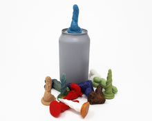 Load image into Gallery viewer, A small pile of various colors and designs of the silicone mini charms with a soda can for scale on a white background. A blue Lust Burster mini is on top of the soda can.