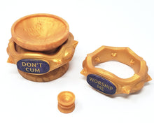 Load image into Gallery viewer, A gold King Noire Royal Fetish Anniversary Double-Sided Suction cup with an Edging Body Band around it, next to a mini suction cup and another Edging Body Band on a white background