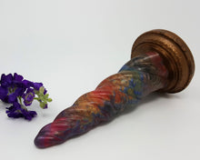 Load image into Gallery viewer, A Rainbow Agate color Unicorn Horn insertable toy on its side with purple flowers on a white background