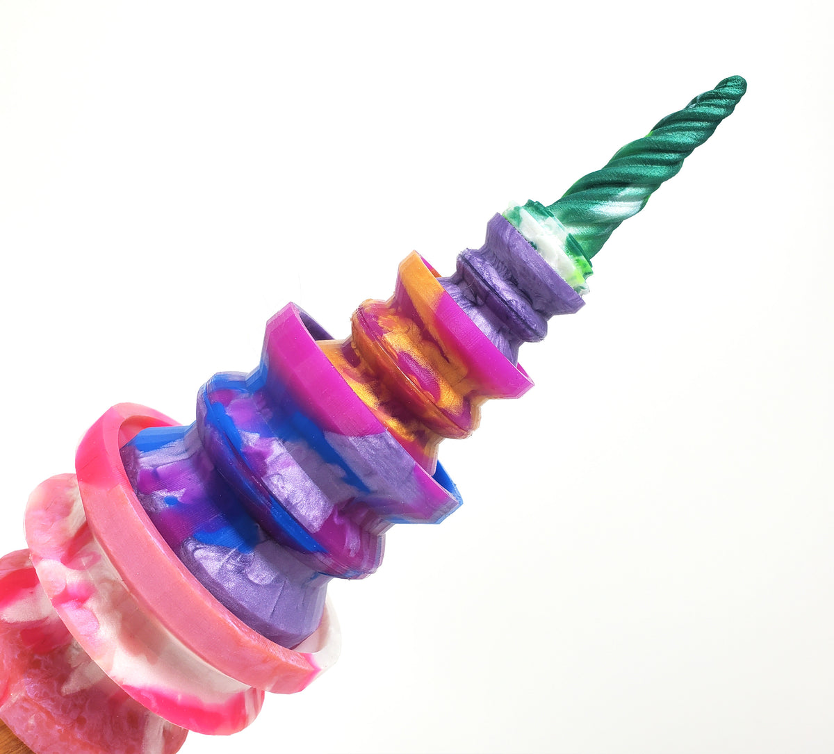 A playful suctioned tower of Double-Sided Suction cups stuck together with a mini suction cup and Unicorn Horn charm at an angle pointing right on a white background