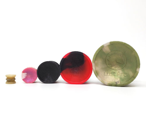 Four sizes of Double-Sided Suction Cups from Lust Arts in a row on their sides with a charm mini suction cup on the end
