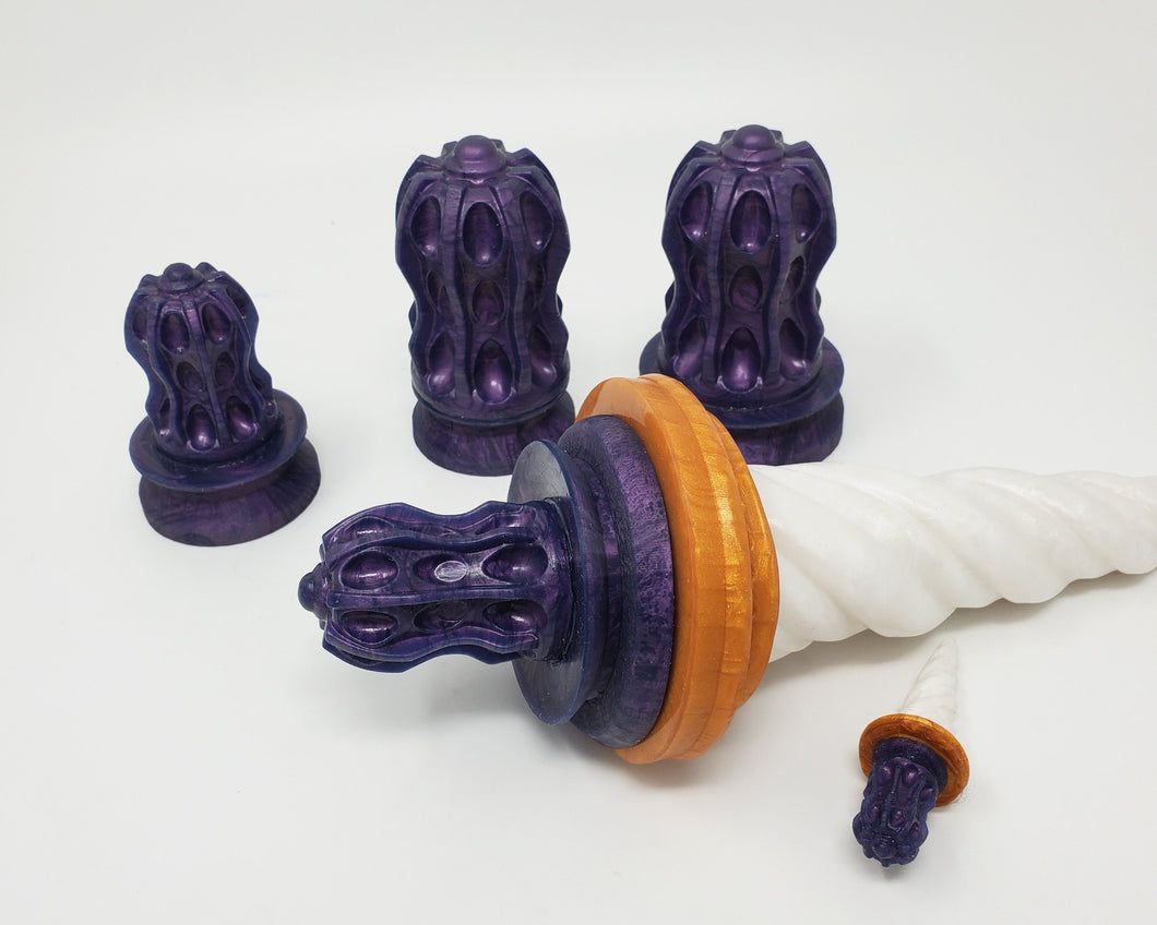 Four different sizes of Thruster Suction Cup Handles with one attached to the base of a Unicorn Horn insertable toy on a white background, mini handle and Unicorn charm in front