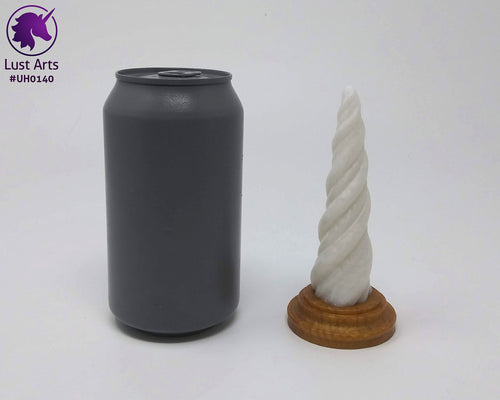 Photo of a Unicorn Horn insertable toy next to a soda can for scale on an off-white background