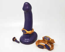 Load image into Gallery viewer, A dual-density FEMDOM insertable adult toy with an Edging Body Band next to a stack of bands at a mini charm on a white background
